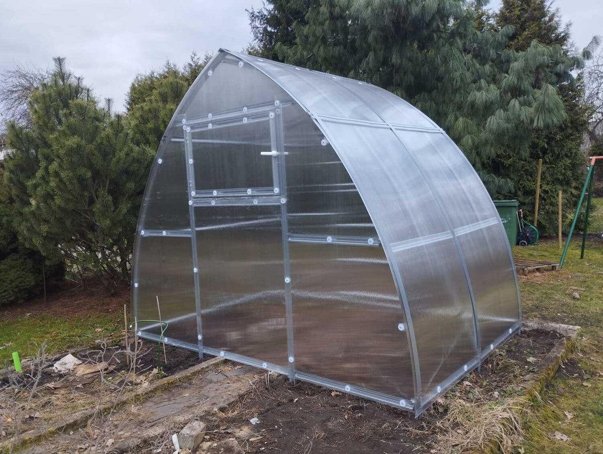 Serre de jardin L'Apogée en polycarbonate installée dans un jardin